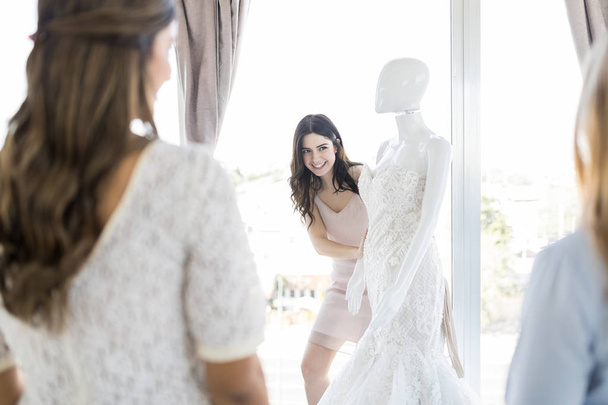 Atractiva compradora expresando su deseo de comprar elegante traje de boda en maniquí
 - Foto, imagen