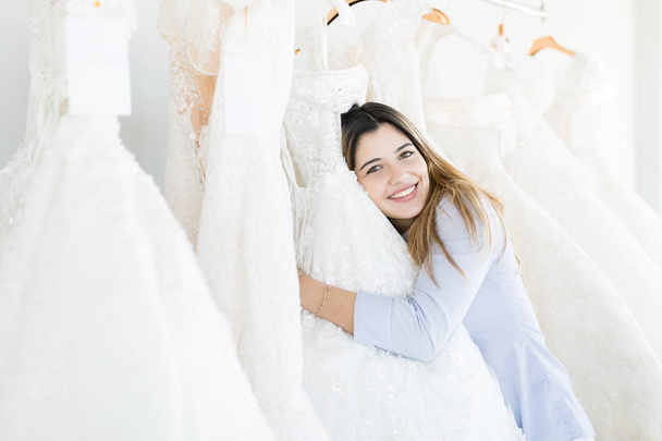 Ładna kobieta klienta przytulanie jej ulubiony biała suknia w sklepie odzieżowym - Zdjęcie, obraz