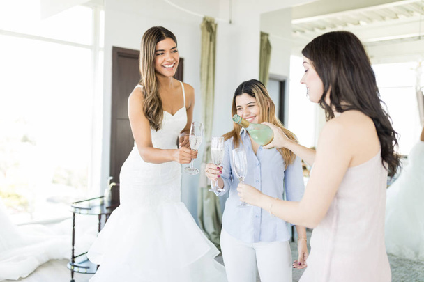 Acquirenti femminili multietniche che bevono champagne per festeggiare nel salone di nozze
 - Foto, immagini