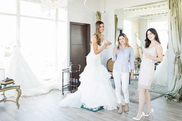 multiethnische Käuferinnen haben Spaß nach dem Kauf eines weißen Kleides im Brautmodengeschäft - Foto, Bild