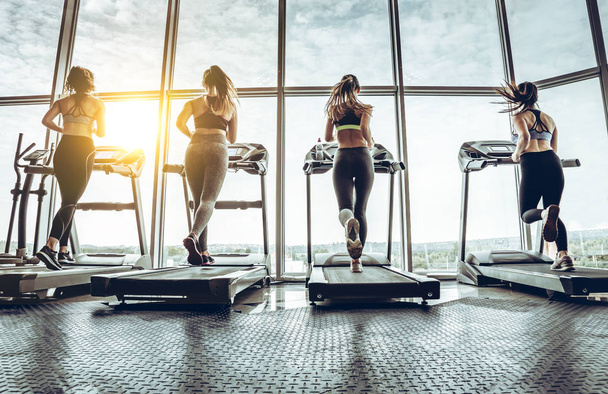 Полная длина женщин, тренирующихся в тренажерном зале. Снимок четырех женщин бегущих на беговой дорожке в спортзале
. - Фото, изображение