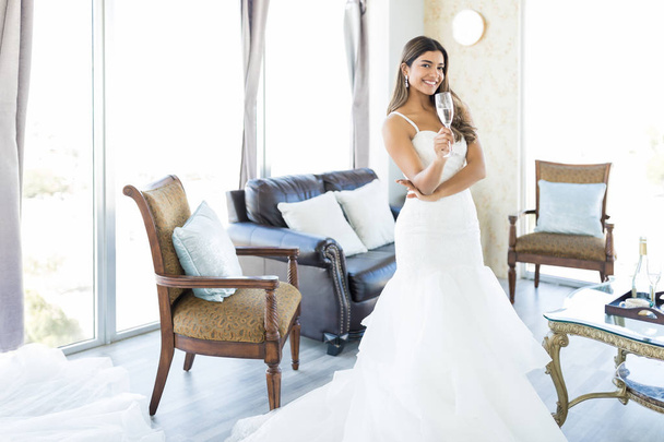 Good looking Latin bride smiling while enjoying champagne at a wedding venue - Fotoğraf, Görsel