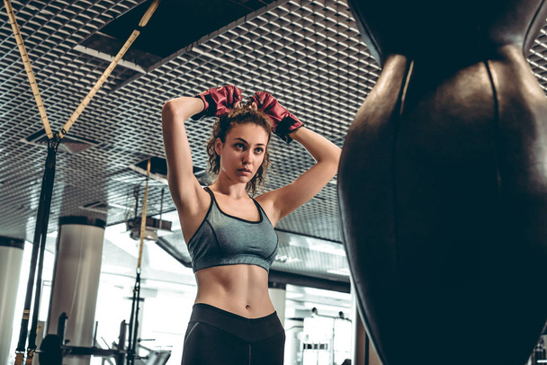 Sport koncept. Mladá žena sportive v Boxerské rukavice poblíž hruška v tělocvičně. - Fotografie, Obrázek