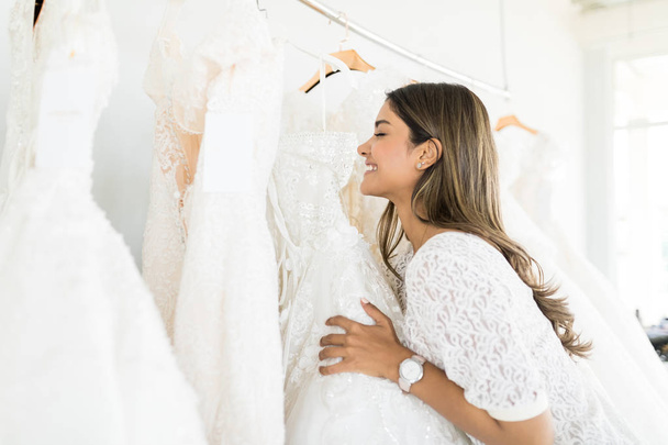 Oldalnézetből a gyönyörű fiatal menyasszony lány esküvői ruha menyasszonyi üzlet kiválasztása - Fotó, kép