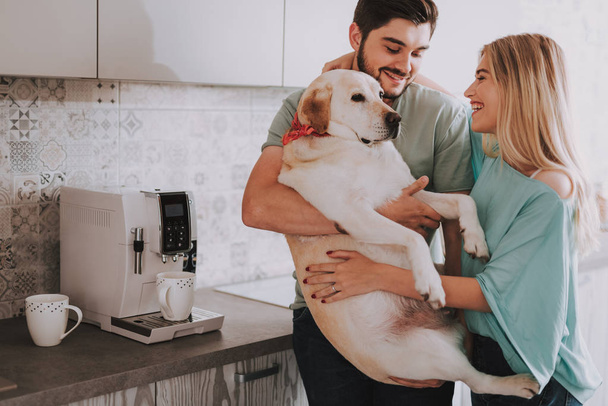 Young laughing couple with their dog in kitchen - Foto, afbeelding