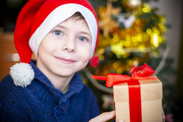 The boy in the hat of Santa Claus to the Christmas tree - Foto, Bild