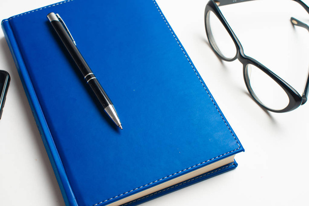 メガネとペン、ノート メガネを掛けて本、メガネ、メガネとペン、お茶のカップが付いている本の青いノートをノートブックに書く - 写真・画像