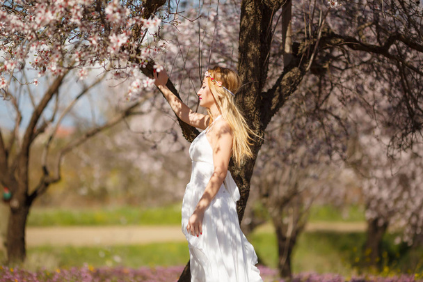 Joven hermosa mujer rubia romántica en vestido blanco en el jardín floreciente
. - Foto, Imagen