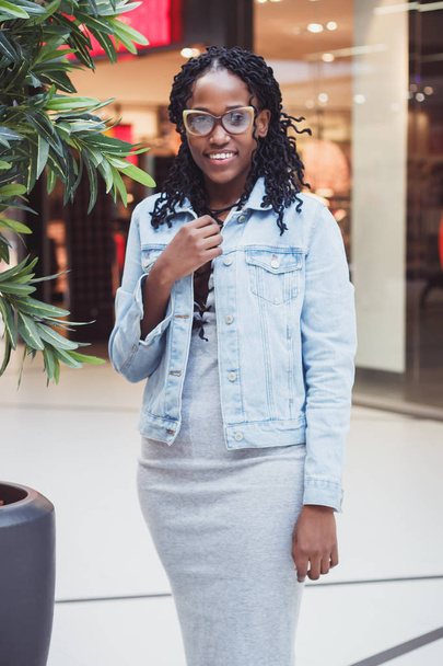 Young dark-skinned woman dressed in casual clothes in the mall, blurred background - Foto, Bild
