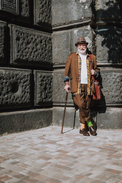 Hipster cheerful old man leaning against the wall - Zdjęcie, obraz