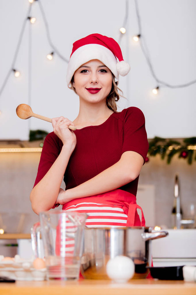 housewife in Santa Claus hat  cooking Christmas dinner - Фото, изображение