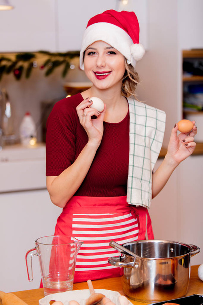 housewife in Santa Claus hat  cooking Christmas dinner - Photo, image