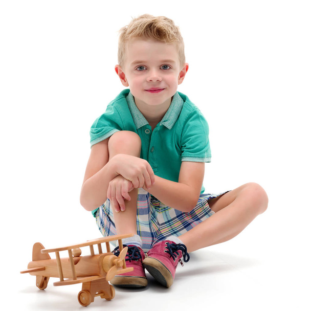 Little boy playing with wooden plane - Fotó, kép