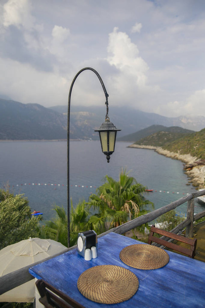 mesa de comedor con vista al mar, dos servicio de mimbre en la mesa, vista a la montaña y al mar
 - Foto, Imagen
