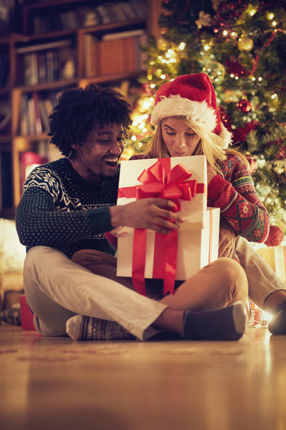 woman open a present by Christmas tree inside - Foto, imagen