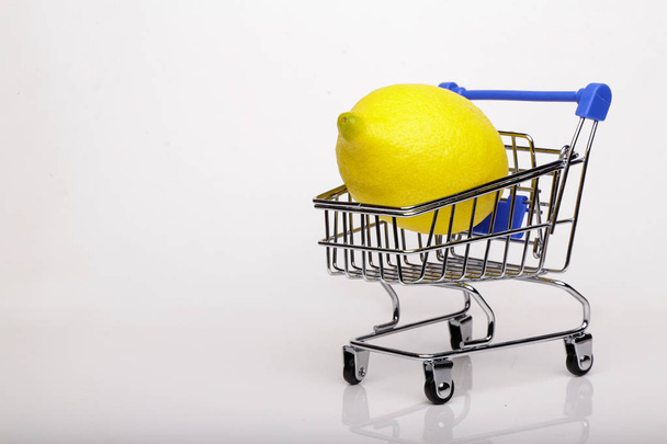 Lemon in shopping cart, shopping trolley isolated white background - Foto, Imagem