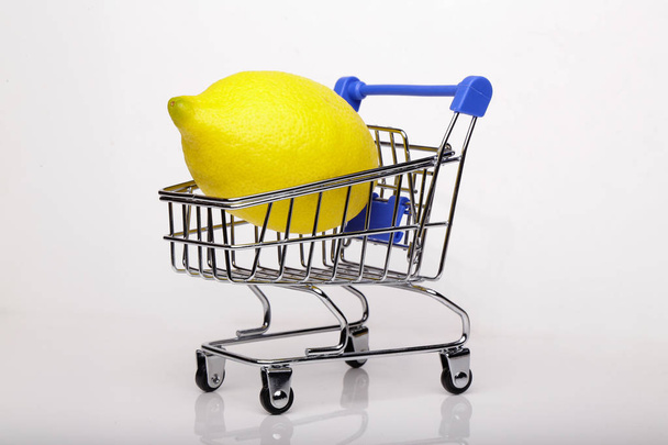 Lemon in shopping cart, shopping trolley isolated white background - Фото, изображение