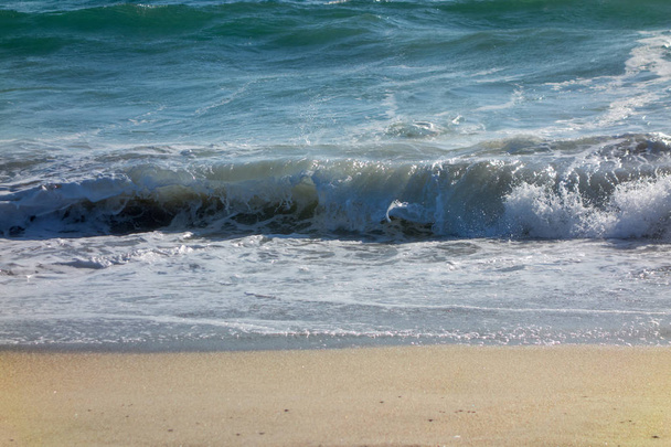 nasser gelber Sand, der von mächtigen rollenden Meereswellen abgeflacht wird - Foto, Bild