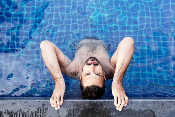 Portrait of a young handsome brutal latin man in an outdoor pool. Attractive guy with a beard  - Fotografie, Obrázek