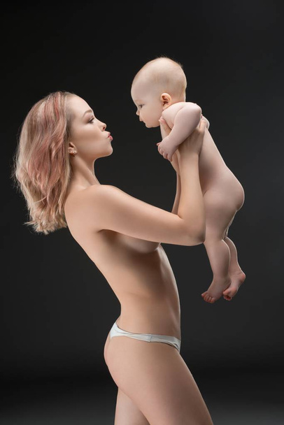 Pretty mother topless holding her baby profile shot - Foto, Imagen