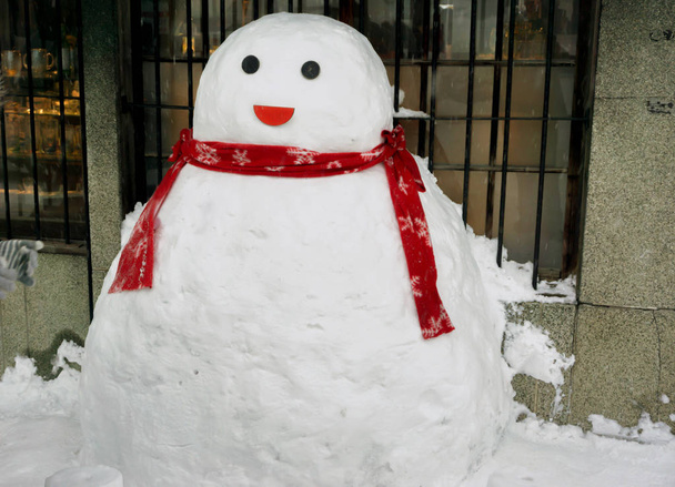 かわいい雪だるま冬の季節で雪の床と窓の前面に赤いスカーフを着用します。. - 写真・画像