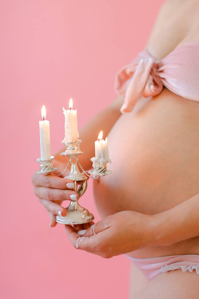 Primo piano donna incinta in biancheria intima tenendo pancia e mantenendo le candele
. - Foto, immagini