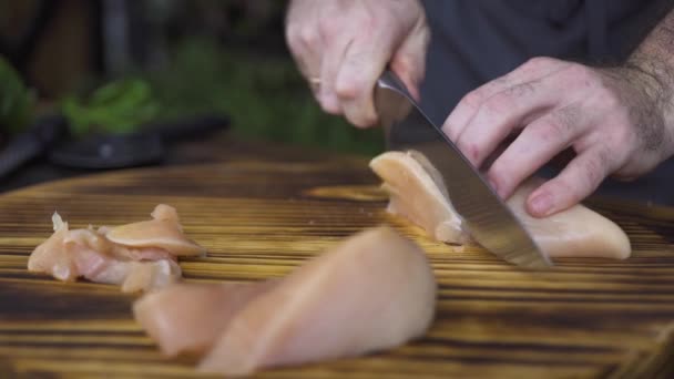 Chef cook cutting raw chicken fillet with knife on wooden table. Male hand cutting on slices chicken meat. Process preparation healthy food. Protein nutrition and fitness diet. Cooking food concept. - Záběry, video