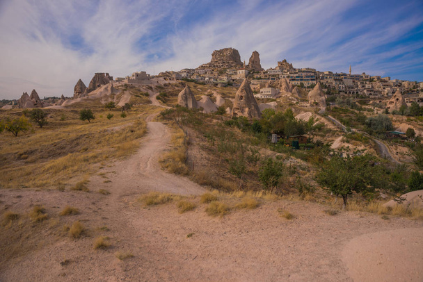 Uchisar, Cappadocia, Nevsehir province, Turkey: The road on the field goes to the city and the fortress of Uchisar. Rock houses and churches. Rock houses and churches. - Valokuva, kuva