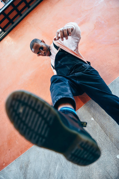 Young black man man kicking towards the ground. Lifestyle concept. - Фото, изображение