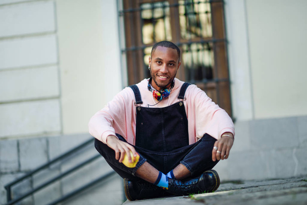 都市の手順の上に座ってリンゴを食べる若い黒人男性。ライフ スタイルのコンセプト. - 写真・画像