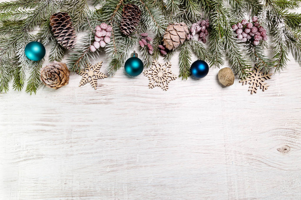 Fir branches with Christmas decorations on a wooden background. Copy space. - Фото, изображение