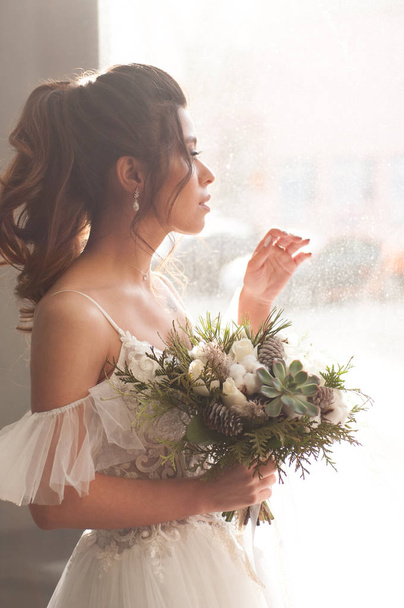 bride with dark hair in a white wedding dress with a bouquet of flowers - Фото, зображення