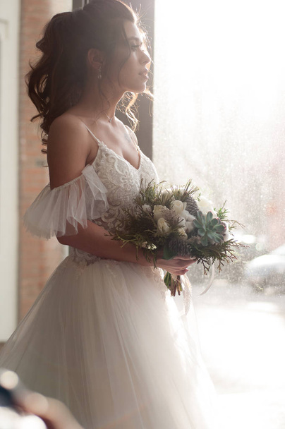 Bride in a white wedding dress with a christmas bouquet of flowers closeup - Fotografie, Obrázek