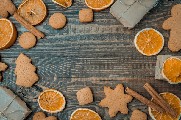 Christmas top view over a brown wooden background with gift boxes packed in a craft paper with dryed oranges, cookies and christmas decorations. Flat lay, copy space, holiday banner. - Φωτογραφία, εικόνα