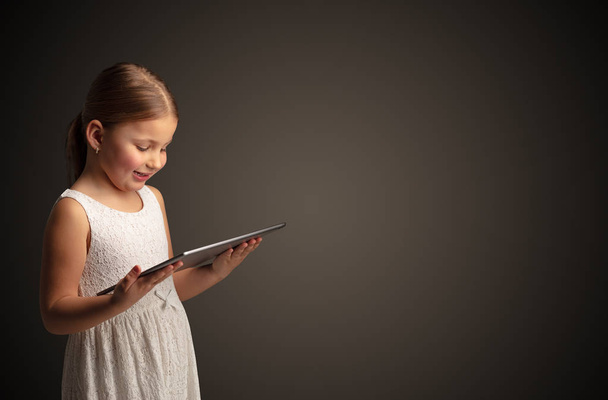 Cute little girl using tablet with dark background - 写真・画像