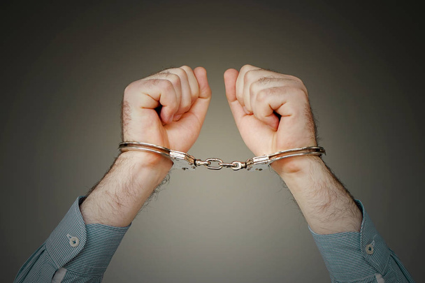 Крупним планом. Заарештований чоловік в наручниках ізольований на сірому фоні. В'язень або заарештований терорист, крупним планом руки в наручниках
. - Фото, зображення