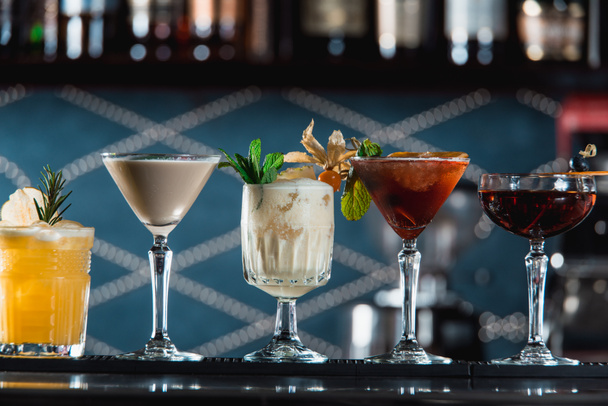 rivi erilaisia värikkäitä alkoholipitoisia cocktaileja baaritiskillä. erimuotoiset lasit
 - Valokuva, kuva