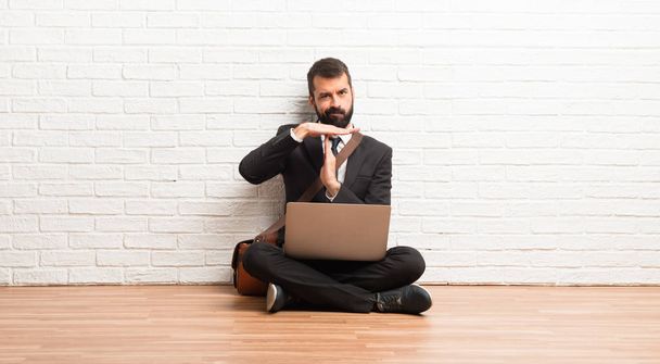 Бізнесмен зі своїм ноутбуком сидить на підлозі роблячи стоп жест з її рукою, щоб зупинити дію
 - Фото, зображення