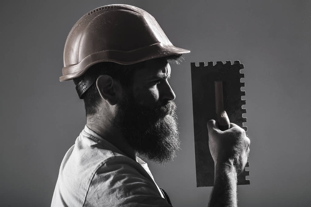 Tool, trowel, handyman, man builder. Mason tools, builder. Bearded man worker, beard, building helmet, hard hat. Builders in hard hat, helmet. Mason plastering. Plastering tools. Black and white - Photo, Image