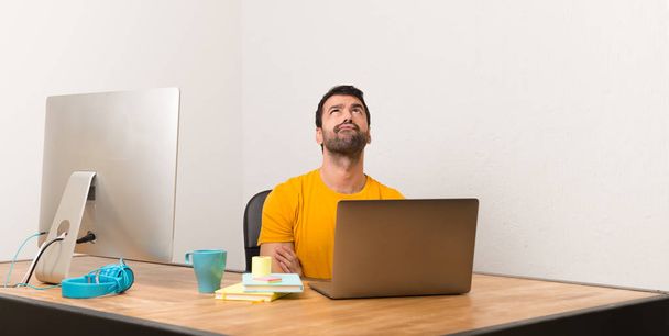 Ember dolgozik egy irodában, komoly arccal felnézett laptot - Fotó, kép