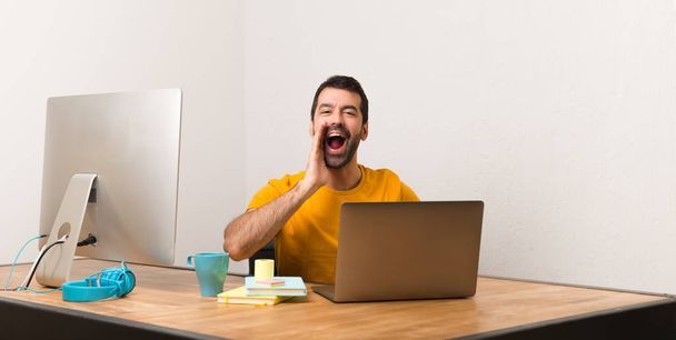Mann arbeitet mit Laptop in einem Büro schreit mit weit geöffnetem Mund zur Seite - Foto, Bild