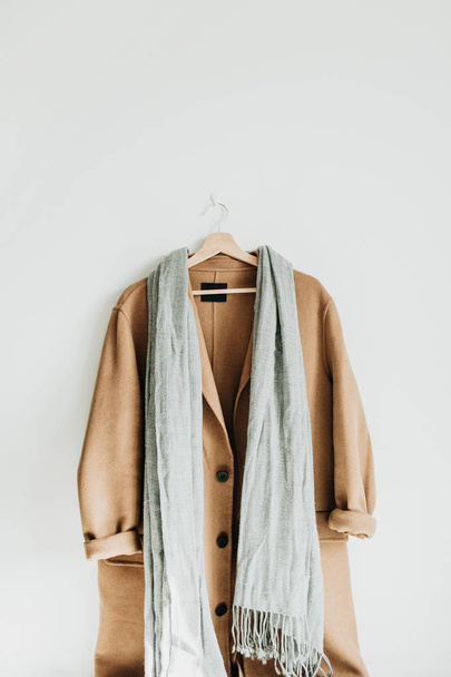 Bej renkli yün kadın ceket ve beyaz duvar askı üzerinde gri eşarp. Kadın moda kış bez kavramı. - Fotoğraf, Görsel