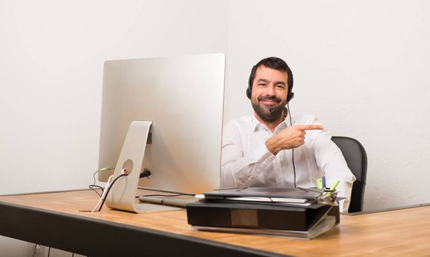 Telemarketer man in a office pointing finger to the side in lateral position - Photo, Image