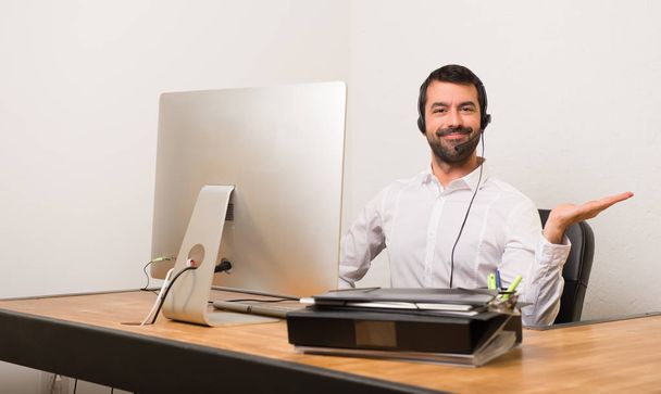 Hombre telemarketer en una oficina con espacio de copia imaginario en la palma de la mano para insertar un anuncio
 - Foto, Imagen