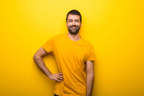 Man on isolated vibrant yellow color posing with arms at hip and smiling - Fotó, kép