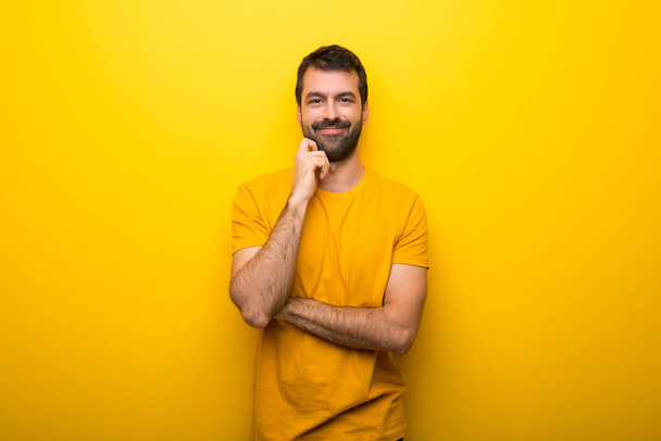 Homem na cor amarela vibrante isolado sorrindo com uma expressão doce
 - Foto, Imagem