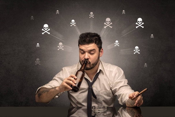 П'яний чоловік сидить за столом з концепцією черепів
 - Фото, зображення