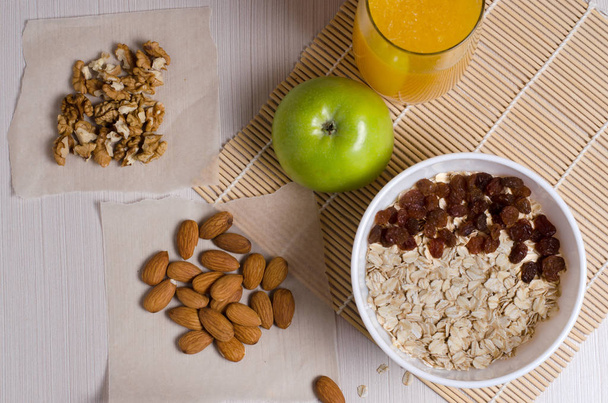 Gesunde Ernährung. Obst, Nüsse, Haferflocken, Orangensaft auf einem weißen Tisch. flache Ansicht von oben - Foto, Bild
