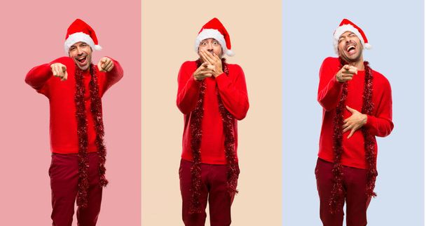 Conjunto de Homem com roupas vermelhas celebrando as férias de Natal apontando com o dedo para alguém e rindo
 - Foto, Imagem