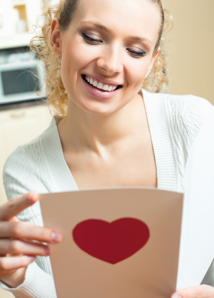 Cheerful smiling woman, reading valentine card - Fotó, kép